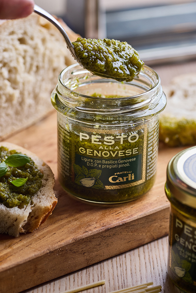 Gesto di estrarre da un vaso di pestro Fratelli Carli un cucchiao di Pesto.