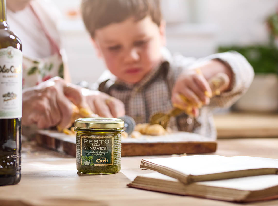 Vasetto  di  Pesto Carli in ambientazione domestica con nonna e nipote che cucinano