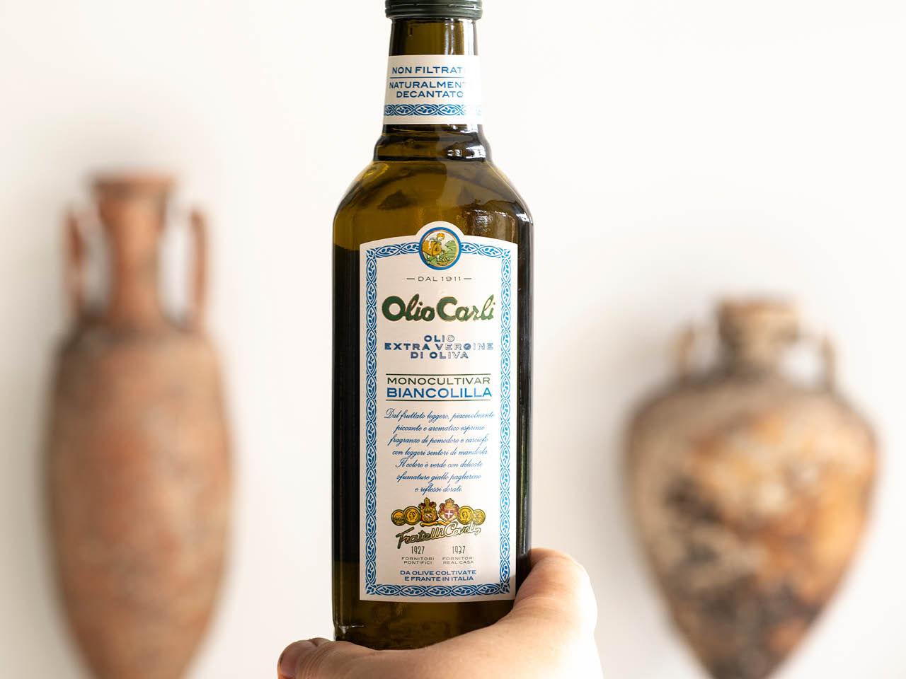 Bottiglia di Olio di Oliva extra vergine Biancolilla tenuta in una mano